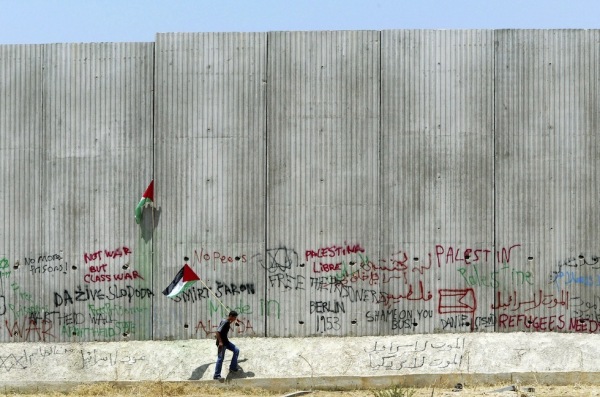 Un palestinese davanti al muro eretto dal governo israeliano nella città di Qalqilya, in Cisgiordania