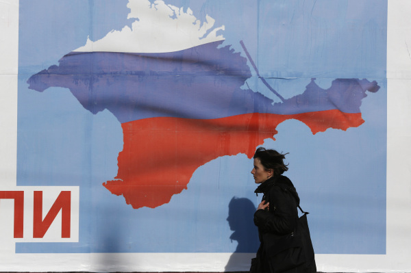 Woman walks by a poster in the Crimean port city of Sevastopol