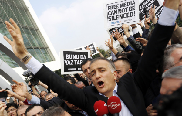 Zaman editor-in-chief Dumanli, surrounded by his colleagues and plainclothes police officers, reacts as he leaves the headquarters of Zaman daily newspaper in Istanbul