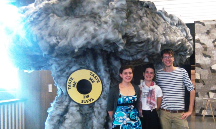 Emma Pritchard, Marie Cucurella e Simon Ott em frente a uma escultura da Bomba Atômica exibida na conferência.