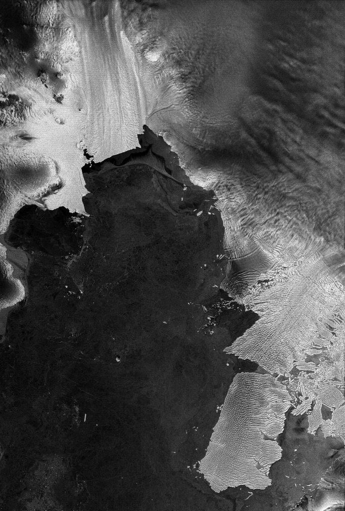 Vista desde el satélite Envisat: Pine Island (parte central de arriba) y el glaciar Thwaites (parte inferior derecha), los dos glaciares antárticos que se desplazan a mayor velocidad que cualquier otro glaciar en la Antártida. Se muestran tal y como fueron vistos el 15 de agosto de 2011 por el radar ASAR de la Agencia Espacial Europea (ESA). Un iceberg identificado como B-22A, se separó del glaciar Thwaites hace pocos años, pero se mantiene cerca como si hubiese sido anclado a un banco submarino. Este iceberg mide 80×45 km, y el tamaño de la imagen captada por Envisat es de 226×335 km.