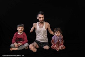 Porträt eins Mannes mit fehlenden Gliedmaßen und zwei Kindern