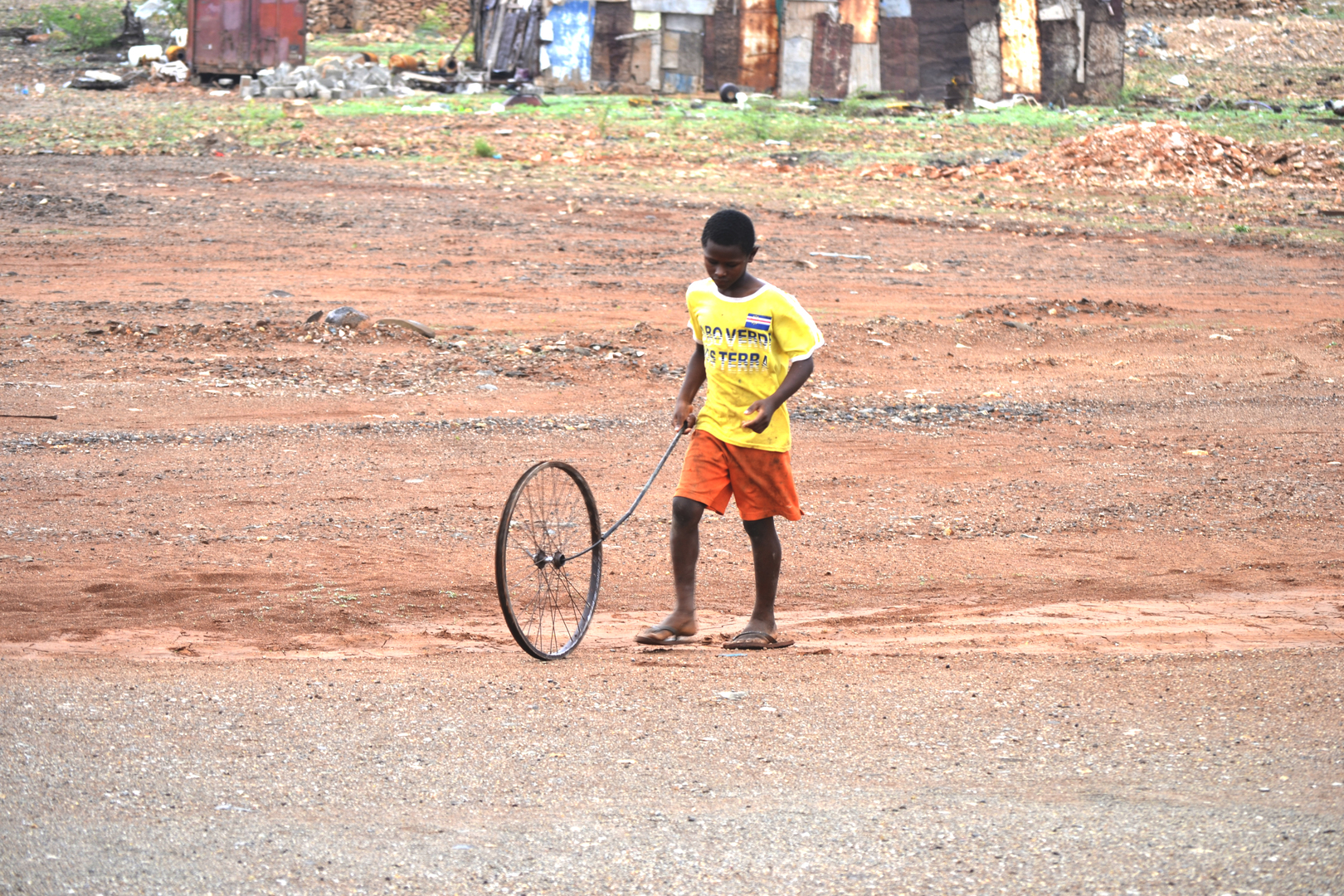 Kind, das auf einer Brache mit einem Rad spielt