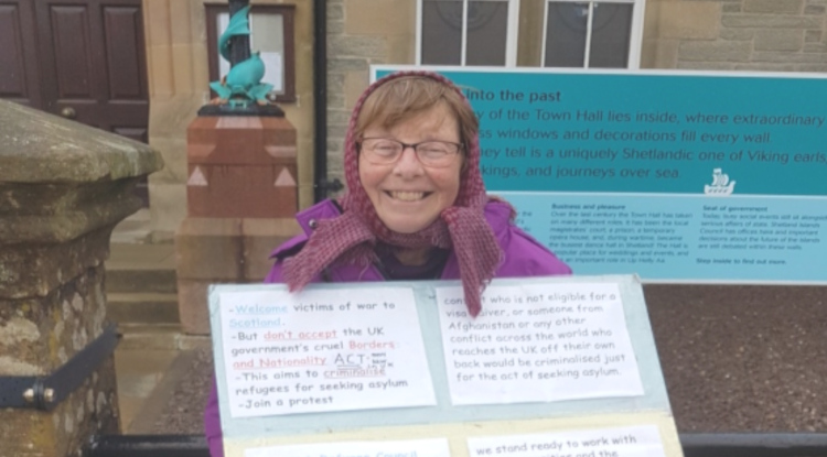 Anne Dobbing tenant sa pancarte en faveur des droits de réfugiés