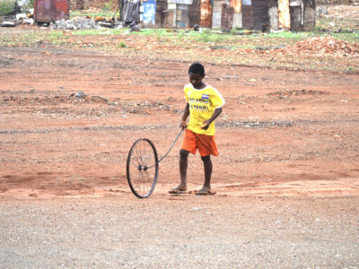 Kind, das auf einer Brache mit einem Rad spielt