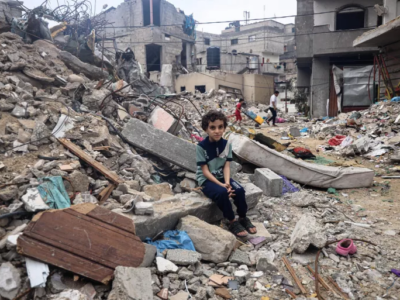 A boy sits in rubble in Gaza.