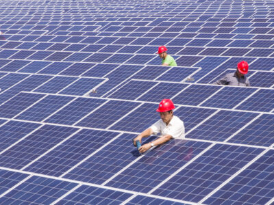 Workers install solar panels on the rooftop of a building at a textile factory in Nantong city, east China's Jiangsu province.