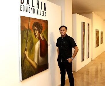 The artist— Edmond Rivera poses for a photo in front of his exhibition. Photo by NCCA Public Affairs & Information Office – Jonathan Vergara.